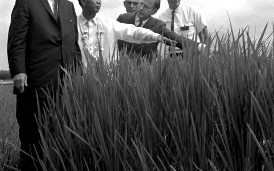 Philippine President Ferdinand Marcos gives President Lyndon Johnson a tour of an experimental rice paddy during the Manila Summit.