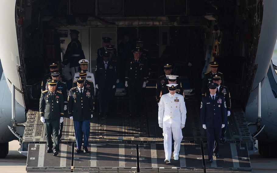 A multinational honor guard walks off an Air Force transport plane at Osan Air Base, South Korea on Wednesday, Aug. 1, 2018. Fifty-five cases presumed to be holding the remains of U.S. troops killed in the Korean War began their journey home Wednesday after a formal send-off on base.