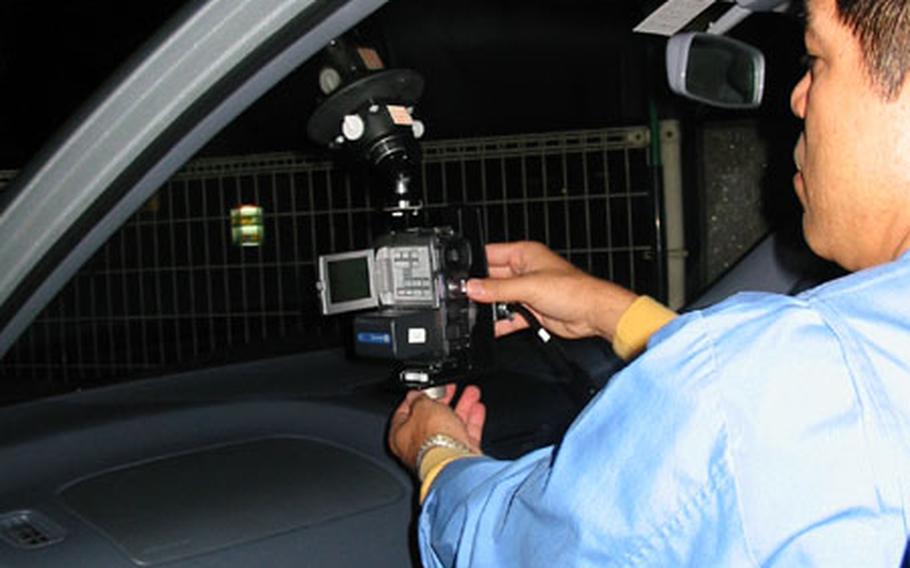 Tatsuo Oshiro, assistant chief for the Okinawa Prefectural Police Department&#39;s Bosozoku Unit, prepares his camera for another night&#39;s filming of the antics of Okinawa&#39;s "Noise Kids."