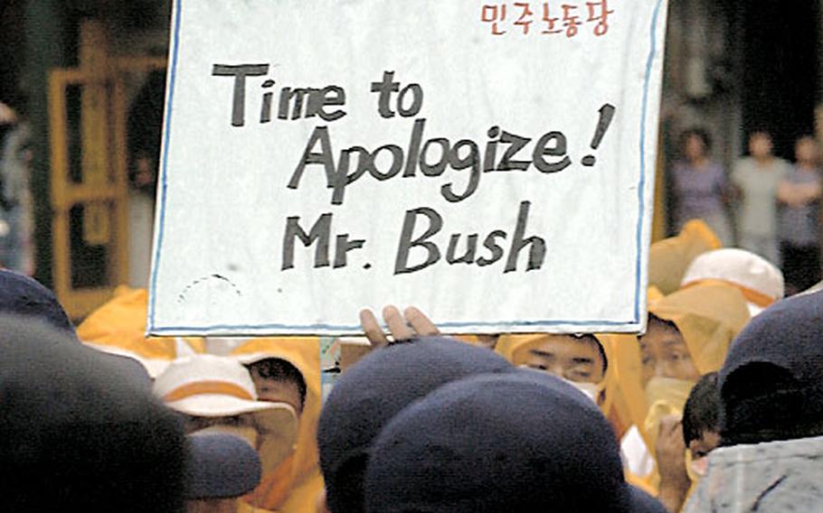 A protester holds a sign demanding an apology from U.S. President Bush outside Osan Air Base, South Korea, in August. More than 200 people gathered to protest a June 13 accident in which a U.S. Army vehicle crushed two South Korean girls.