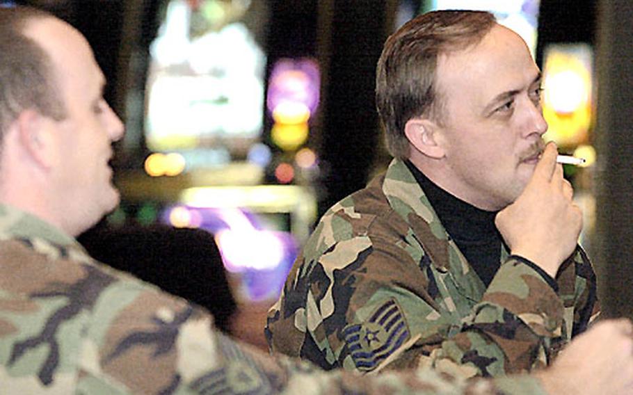 Air Force Tech. Sgt. Chris Preniss, left, and Tech. Sgt Damian Cone enjoy a smoke while watching college basketball at the Shogun Lounge in Yokota&#39;s enlisted club before a smoking ban at MWR facilities went into effect in December.