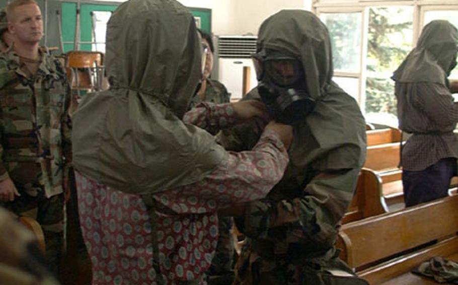 Members of the U.S. Army&#39;s Korean Service Corps Battalion in Taegu, South Korea, last summer practice donning chemical protective gear in a classroom of the Taegu Middle School during annual rehearsal for wartime mobilization. The unit held this year&#39;s exercise in the same place Aug. 20th and 21st.