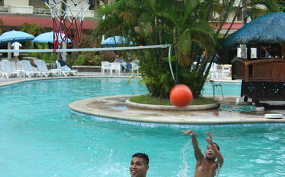 Boys from the Angeles Bahay Bata Center, Angeles City, Philippines, play a game of pool basketball with servicemembers from the 3rd Marine Expeditionary Brigade during a Christmas party at the Holiday Inn Resort, Clark Field.