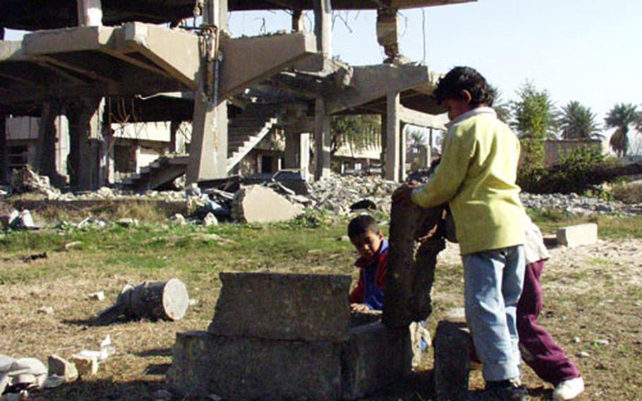 Iraqi children use the rubble to build things outside a bombed Baath party headquarters.