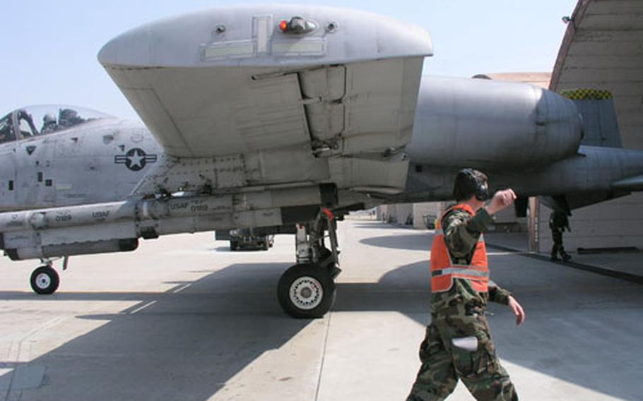 During weeklong combat readiness exercise at Osan Air Base in South Korea, Senior Airman Dusty Surber heads back into a "flow" aircraft shelter after using hand-and-arm signals to guide this A-10 attack plane out of the shelter Tuesday.