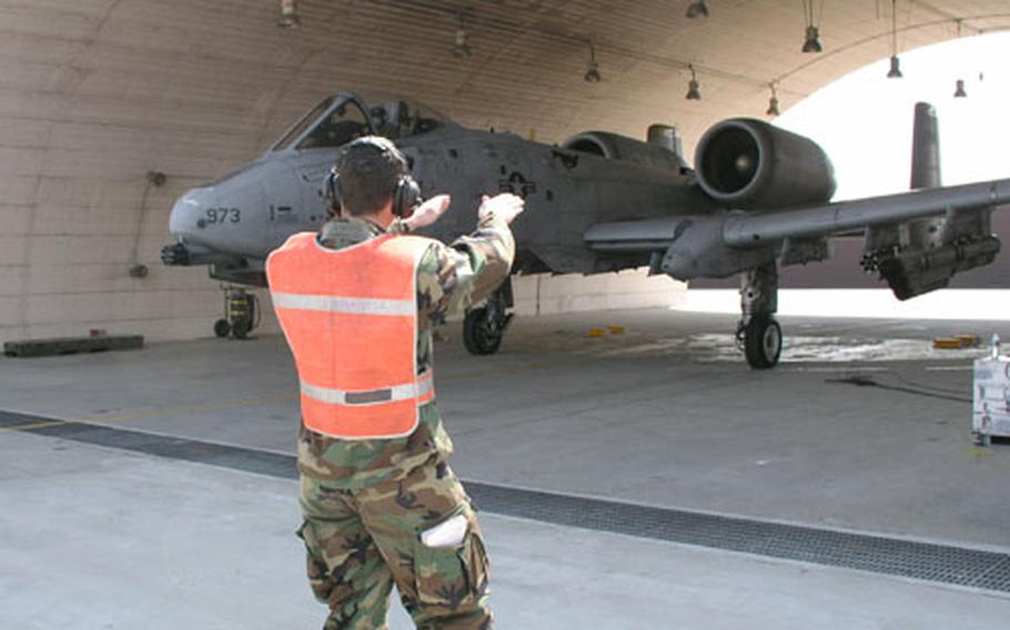 At Osan Air Base, South Korea, Senior Airman Dusty Suber uses hand-and-arm signals to guide an A-10 attack plane from a flow shelter where it has just been refueled with its engines running. Called "hot pitting," the refueling method when used in wartime helps get aircraft just back from a combat mission back into the skies again more quickly.