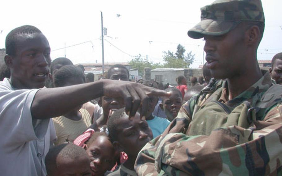 Army Spc. Roowdolf Charles, a 23-year-old Haitian-American fluent in Creole, speaks to Haitians during a recent water distribution and humanitarian aid event in the impoverished Cite Soleil section of Port-au-Prince, Haiti. Charles, with Bravo Company, 9th Psychological Operations Battalion, lived in Haiti until he was 6 years old, when his family moved him to Newark, N.J.