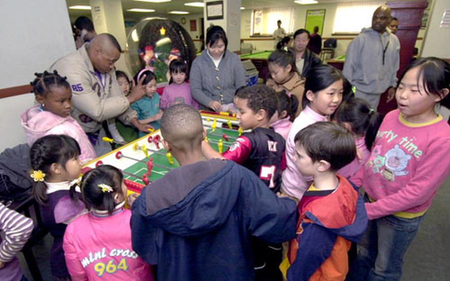 Marine Master Sgt. Jeffery plays foosball with girls from the Sun Duk Orphanage.