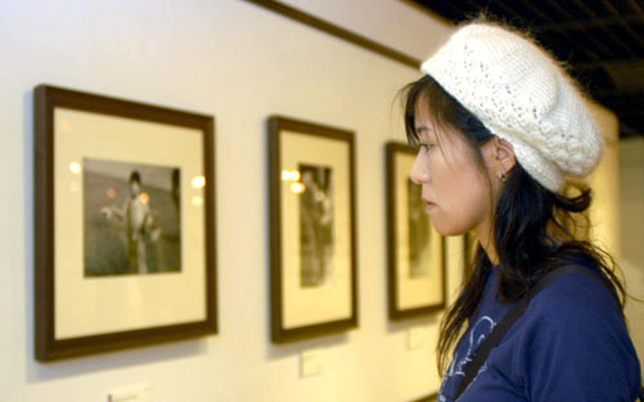 Yoko Kameda looks at artwork by war photographer Robert Capa during a visit to the "Off War" exhibit at Yokohama’s Red Brick Warehouse Number One. The exhibit runs through Dec. 25.