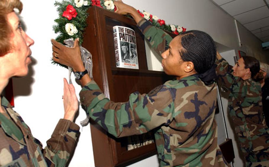 Col. Anita H. McCowen, left, of the Army hospital in Heidelberg, Germany, directs Sgt. 1st Class Sheryl T. Bean, second from left, and Sgt. 1st Class Dorothee J. Smith as they decorate the Gen. Patton display case outside the radiology department of the hospital on Nachrichten Kaserne.