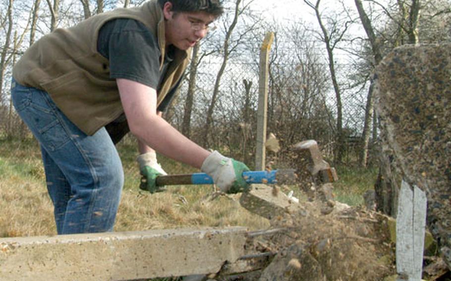 Pieces of concrete fly into the air as Lakenheath High School sophomore Dan Jones wields a sledgehammer during an environmental project for great crested newts.