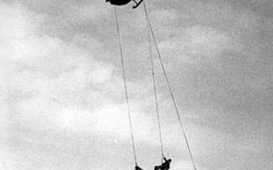 Three U.S. Navy SEALs dangle from helicopter winches after a running takeoff from a Vietnamese beach during a fast-getaway demonstration in 1967.