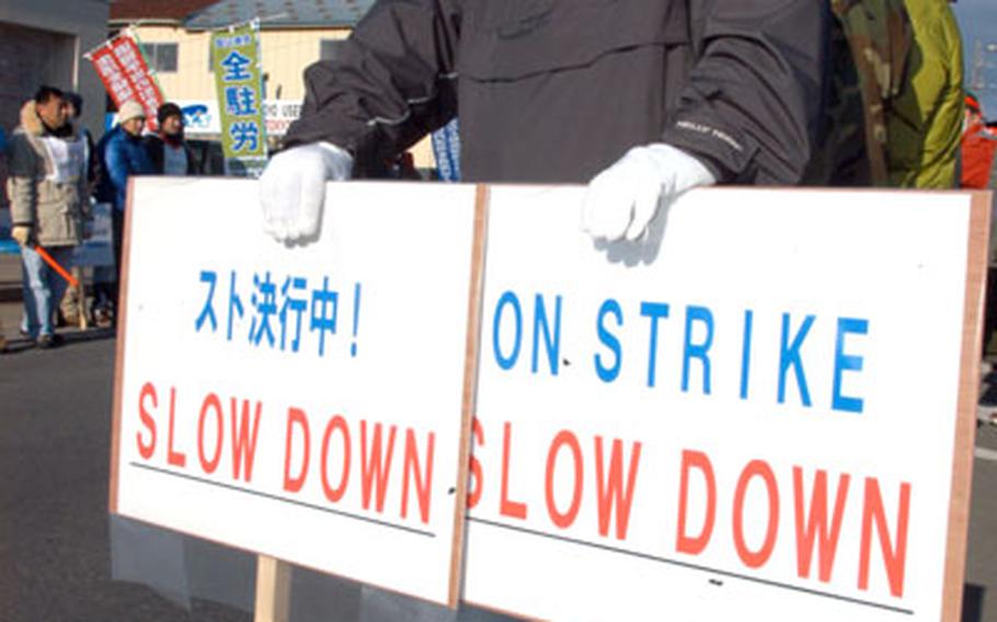 An unidentified Japanese union member holds up "on strike" signs outside Misawa Air Base Friday morning.