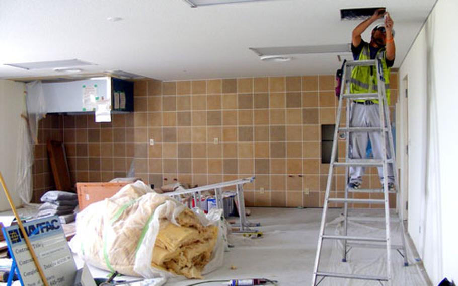 A worker puts the finishing touches on the ceiling of a new kitchenette on the second floor of Bachelor Enlisted Quarters, Building 473, on Camp Foster.