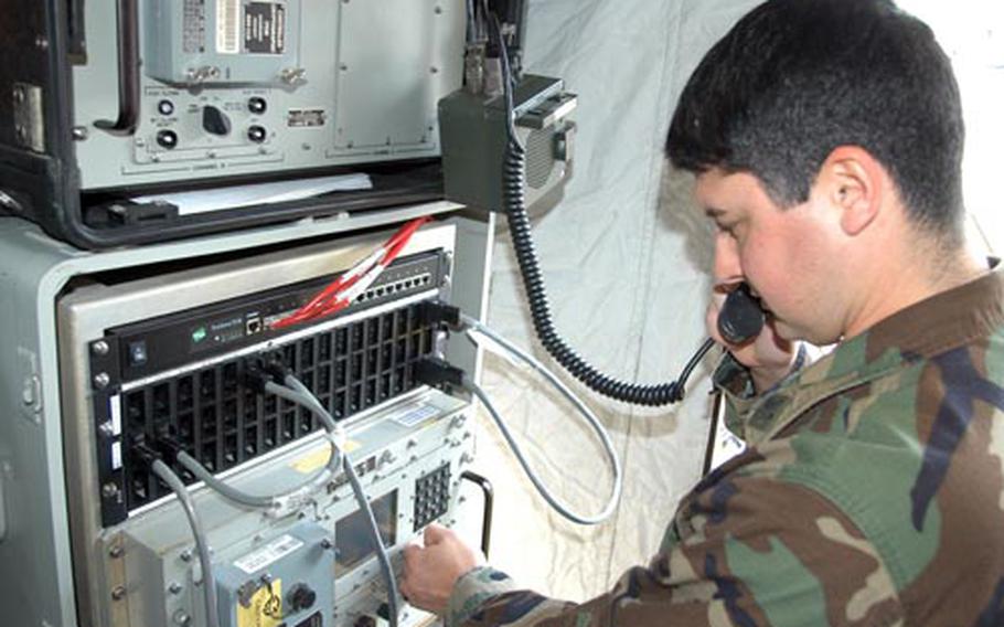 Petty Officer 2nd Class Reuben Hernandez, 29, an electronics technician, demonstrates the use of satellite communications equipment inside expeditionary tents set up by Fleet Maritime Patrol Mobile Operations Control Center West Pacific. The team of 12 sailors deploys around the globe in support of P-3 Orion aircraft.