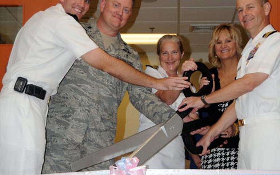 Lt. Stephen Johndreau, left, engineer in charge of the renovations; Air Force Maj. Thomas Cheatham, second from left, wtih 18th Medaical Operations Squadron on Kadena Air Base; Cmdr.Elizabeth Tipton, third from left, department head or of obstetrics and gynecology and maternal fetal medicine; Lorie Zilmer, fourth from left, wife of Lt. Gen. Richard C. Zilmer; and Capt. Stephen Pachuta, executive officer of the hospital, cut the ribbon at the unveiling of the U.S. Naval Hospital&#39;s newly-renovated labor and delivery suite Friday on Camp Lester.