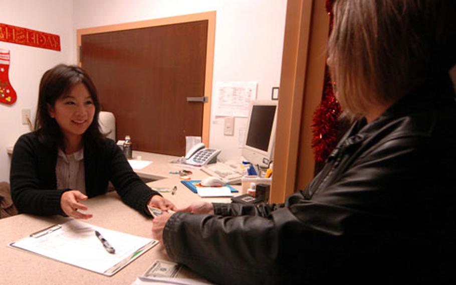 Yoko Maeda, left, assists as Jennifer Benefield exchanges dollars for yen Dec. 24 in the slot machine area of Chili’s Grill and Bar on Yokosuka Naval Base, Japan.