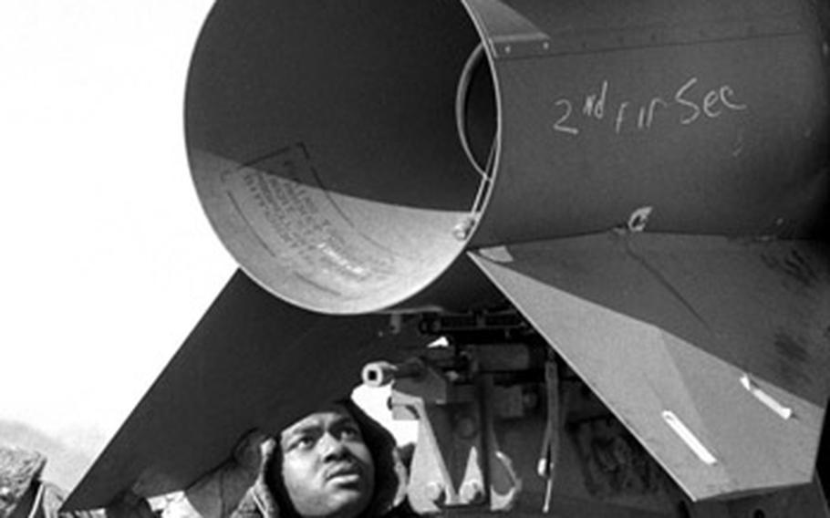 Crewmen from 1st Battalion, 42nd Artillery, check out the fittings on an Honest John missile's tail fins.