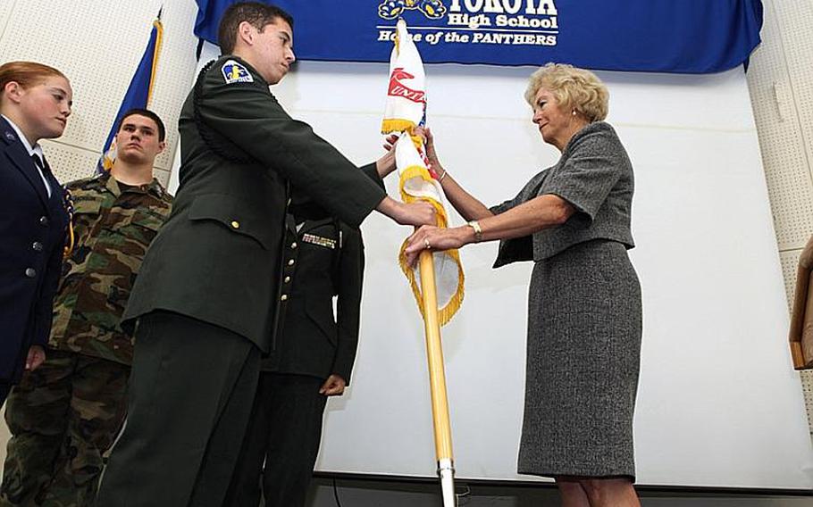 Junior ROTC Cadet Capt. Jayson Hoffart, a junior at Yokota High School, passes the Army Junior ROTC guidon to Diana Ohman, Department of Defense Dependents Schools-Pacific director, during a ceremony Wednesday. After 18 years under the Army Junior ROTC program, Yokota is now an Air Force Junior ROTC unit.