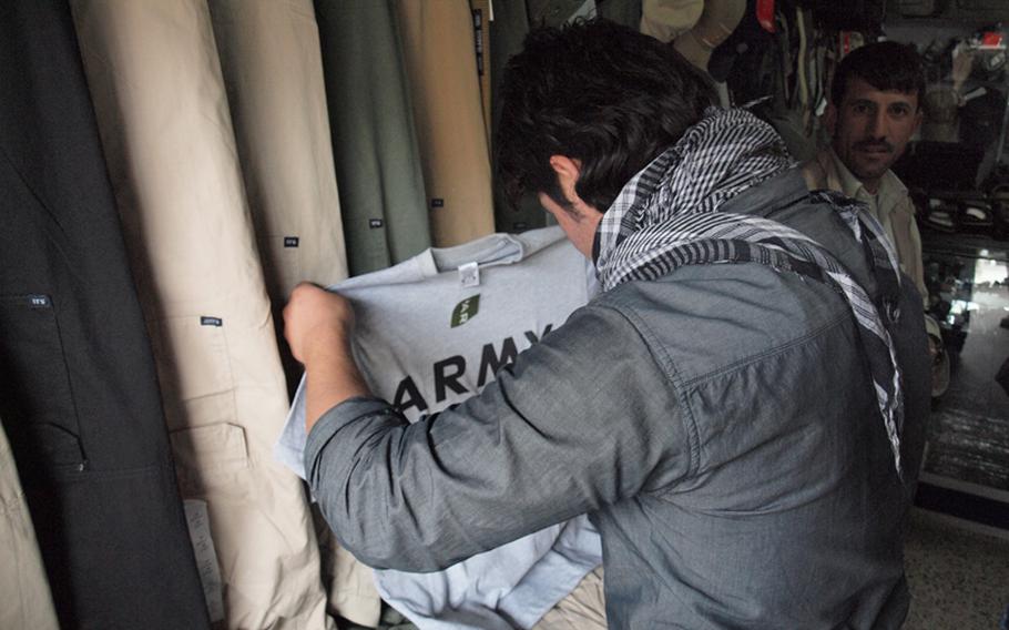 At Kabul’s “Bush Market,” a bazaar specializing in what appear to be pilfered American goods, a young Afghan man checks out a U.S. Army physical fitness T-shirt. The store, one of about 500 in the market, sold 5.11-brand clothing, popular with contractors, socks produced for the U.S. military and other items likely stolen from supply trucks on their way to coalition bases.