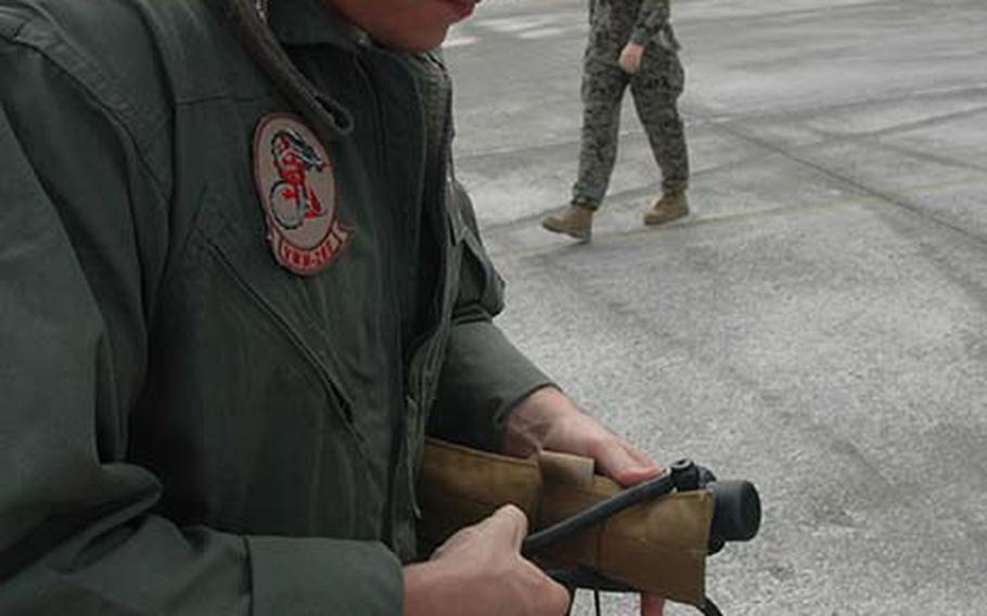 A sergeant and crew member from the 1st Marine Aircraft Wing out of Okinawa, Japan prepares a flight vest for civilian passengers who got to fly in the MV-22 Osprey on Thursday, Dec. 13, 2012 on Guam.