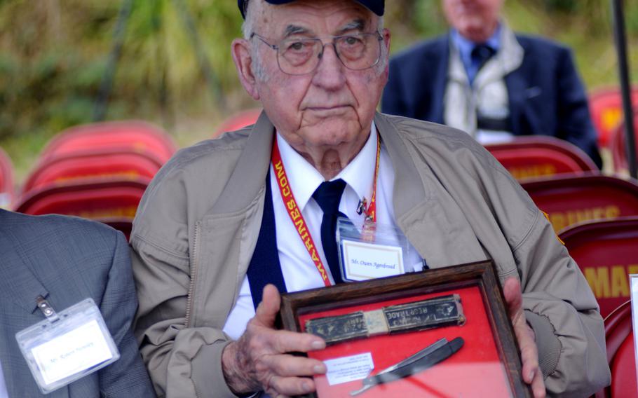 Owen Agenbroad, a veteran of the battle for Iwo Jima, holds up the display of items he collected on the battlefied in 1945 before the 19th Annual Reunion of Honor ceremony on Iwo Jima, Japan, March 19, 2014. Through research, Agenbroad found Yoshikazu Higuichi, the son of the Japanese soldier to whom the items originally belonged, and returned them.