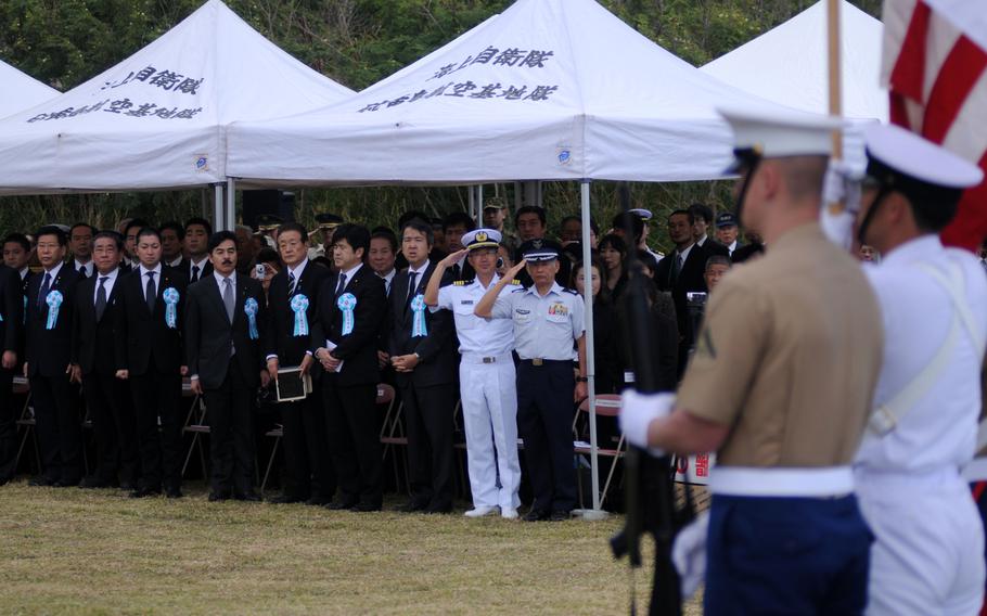 Japanese distinguished guests, including military and government officials, as well as family members of soldiers who fought during the battle for Iwo Jima, salute their national anthem during the 19th Annual Reunion of Honor on Iwo Jima, Japan, March 19, 2014.