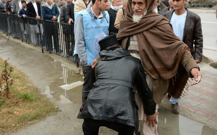 An Afghan police officer pats down a man preparing to vote in Kabul on April 5, 2014. Election day saw widespread violence, but Afghan security forces say they were able to prevent mass casualties or any high-profile attacks.