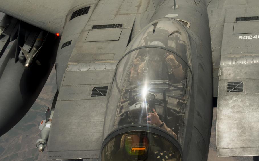 An F-15 fighter pilot and combat systems officer supporting the air campaign against the Islamic State group in Iraq and Syria waves to a KC-135 Stratotanker after the aircraft had completed refueling in midair over Iraq on March 24, 2016.