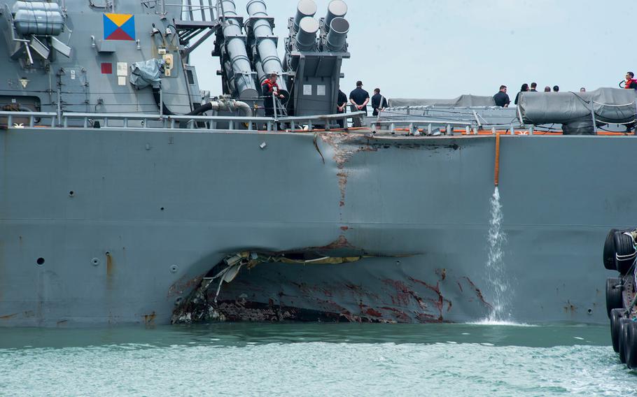 Damage to the portside is visible as the USS John S. McCain steers toward Changi Naval Base, Singapore, following a collision with a merchant vessel, Aug. 21, 2017.