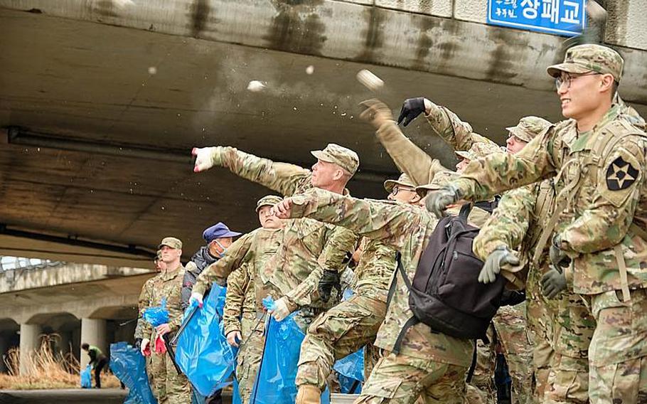 U.S. soldiers from Camp Casey throw eco-friendly biodegradable balls with effective microorganisms into the Shincheon River in Dongducheon, South Korea, Thursday, March 21, 2019.