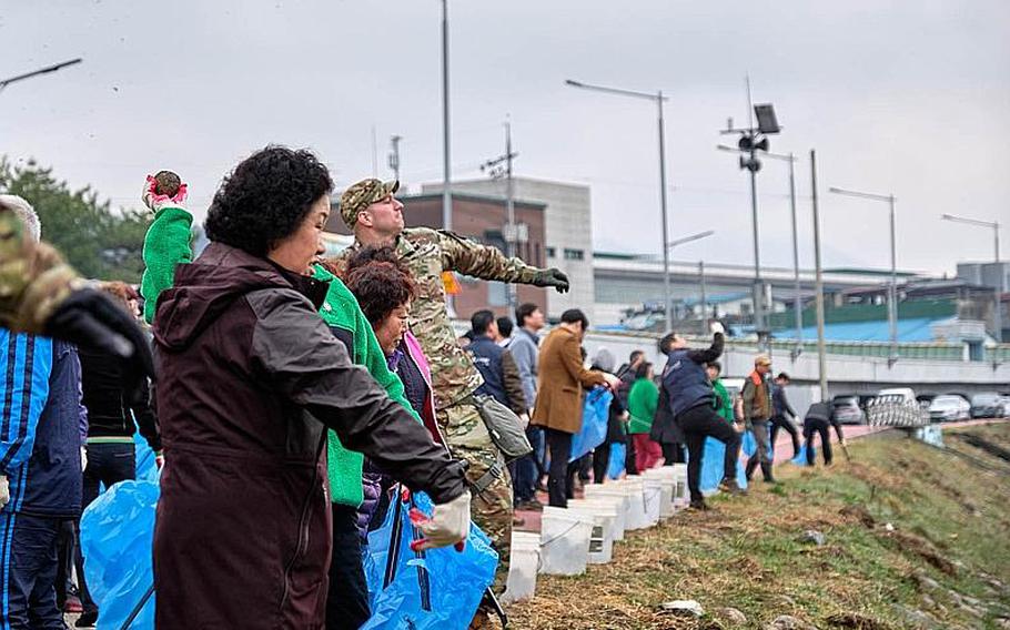 U.S. soldiers from Camp Casey and local volunteers throw eco-friendly biodegradable balls with effective microorganisms into the Shincheon River in Dongducheon, South Korea, Thursday, March 21, 2019.