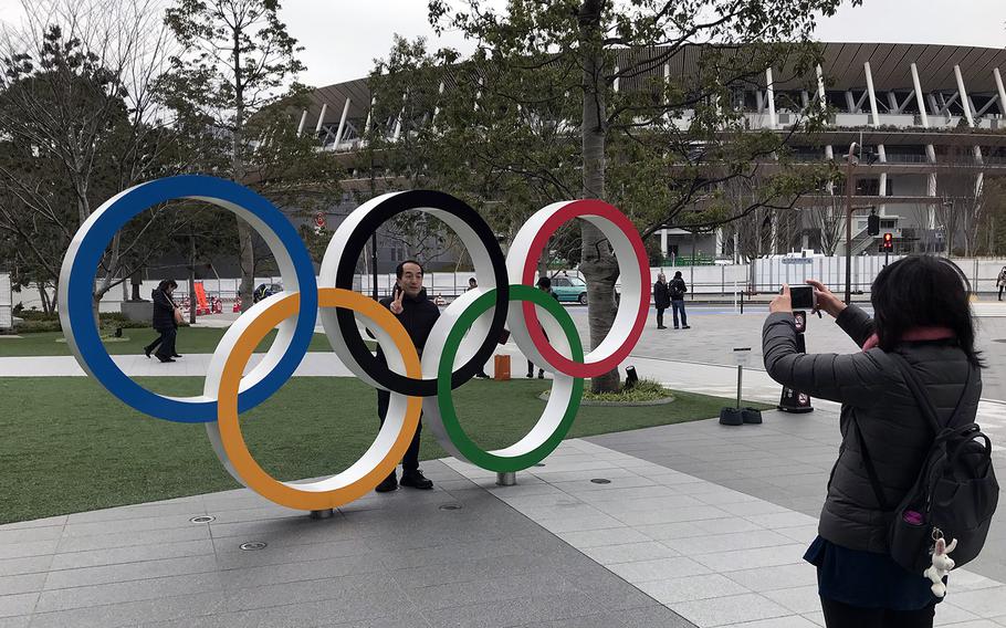 A visitor to the Japan Olympics Museum poses with the Olympic rings near the new National Stadium in Tokyo, Jan. 22, 2020. 