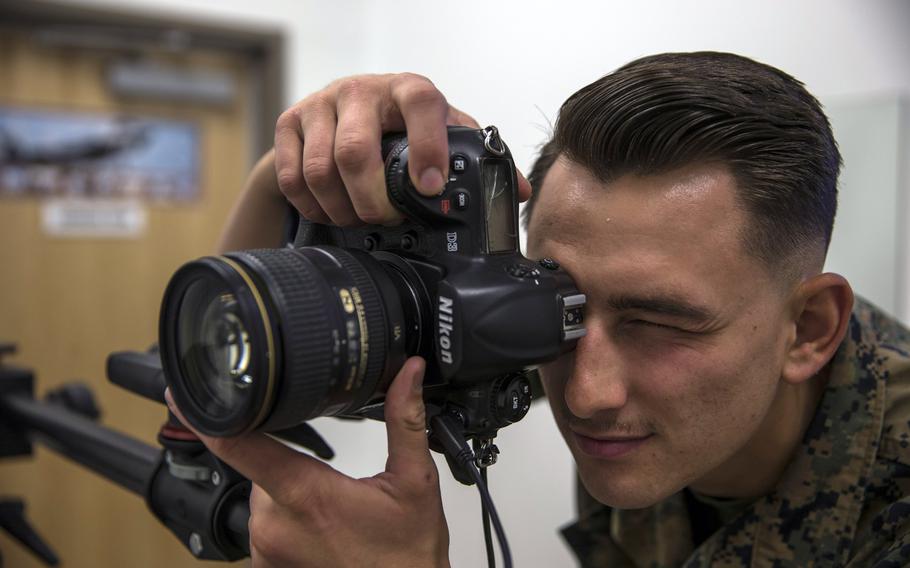 U.S. Marine Corps Lance Cpl. John Hall, a combat photographer, takes a picture in the promotion photo studio at Marine Corps Air Station in Yuma, Ariz., in June 2019. In a move to fight racial and gender bias, photos will no longer be used by promotion boards or in the selection process for opportunities such as training and assignments, the Marine Corps has said.