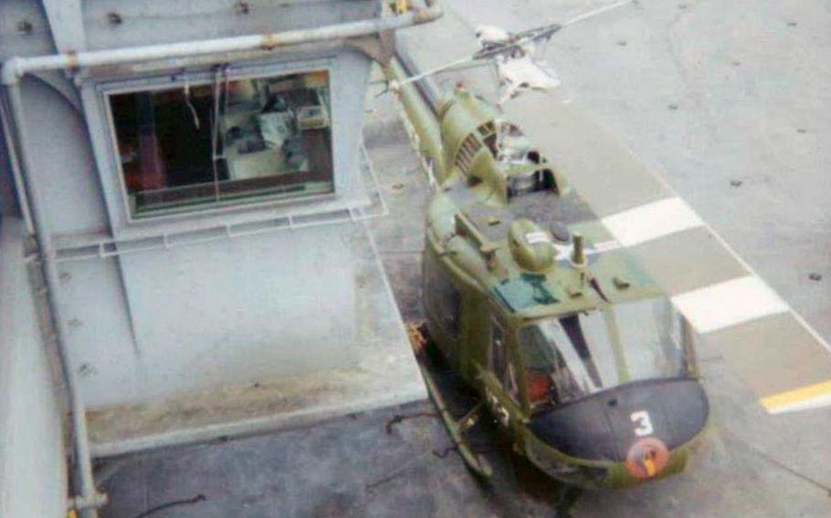 Picture of a Marine Corps Huey helicopter aboard the flight deck of the USS Tripoli out in Yankee Station in the Gulf of Tonkin, off the coast of South Vietnam sometimes between June and July 1972.