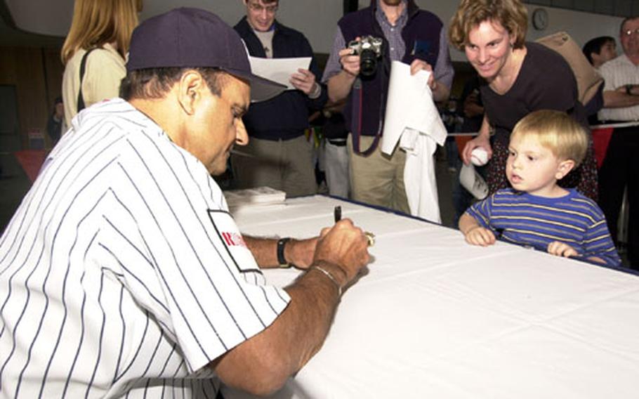 Joe Torre, New York Yankees manager, signs a baseball for Liam Dreher during a visit to Camp Zama Sunday.