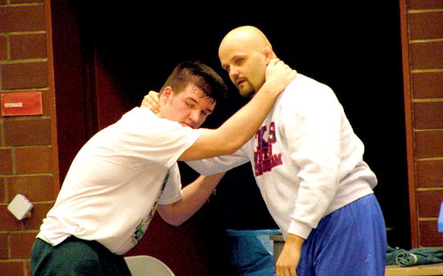 Volunteer wrestling coach Gary Steffensmeier, right, shows European 215-pound champion Cole Maxey how to begin a takedown move during a team practice session at Ramstein High School, Germany.