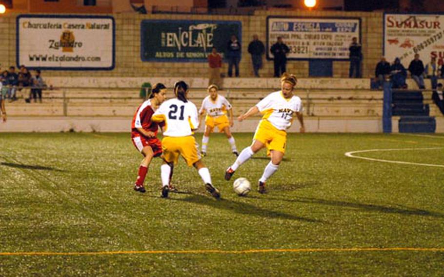 Navy midfielders Julie Reynolds and Christine Calderon get the ball from a U.D. Mairena player during a scrimmage in Seville, Spain.