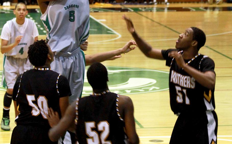 Kubasaki's Xavier Price (5) shoots over Kadena defenders Josh Dyer (50), Savon Woodie (52) and Preston Harris (51) during Thursday's Okinawa Activities Council boys basketball season series finale at Kubasaki High School. The Dragons beat the Panthers 76-67 and won the season series 3-1.