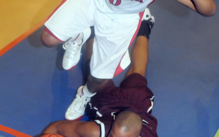 Malik White (0) of Nile C. Kinnick leaps over David Eason of Matthew C. Perry as the ball goes out of bounds during the boys opening game in the 2012 DODDS Japan basketball tournament at Yokota High School. The Red Devils beat the Samurai 64-43.