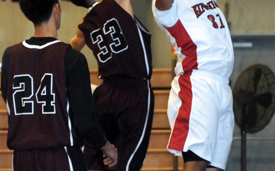 Toshiki Primus (33) of Matthew C. Perry blocks a shot by Sinclair Horton (31) of Nile C. Kinnick during the boys opening game in the 2012 DODDS Japan basketball tournament at Yokota High School. The Red Devils beat the Samurai 64-43.