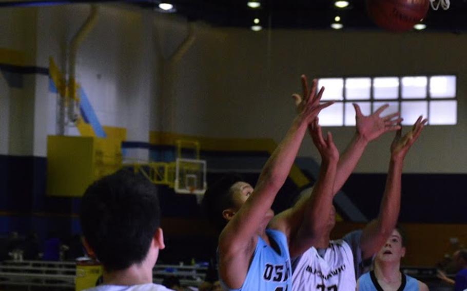 Osan's Sean Copia and Humphreys' Daiquan Wilson battle for a rebound, while  Humphreys' Brice Bulotovich and Osan's Bryce Neuse look on during a Far East basketball tournament game Tuesday.