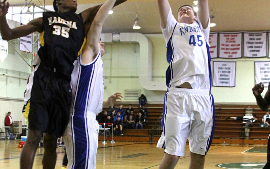 Christian Academy Japan's  Brenton Driscoll grabs a rebound while teammate Drew Erwin screens out Kadena's Boysie Gordon.