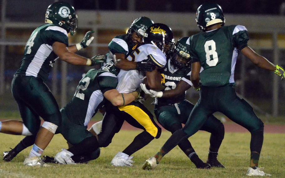 Kadena running back Jason Bland gets gang-tackled by a host of Kubasaki defenders.