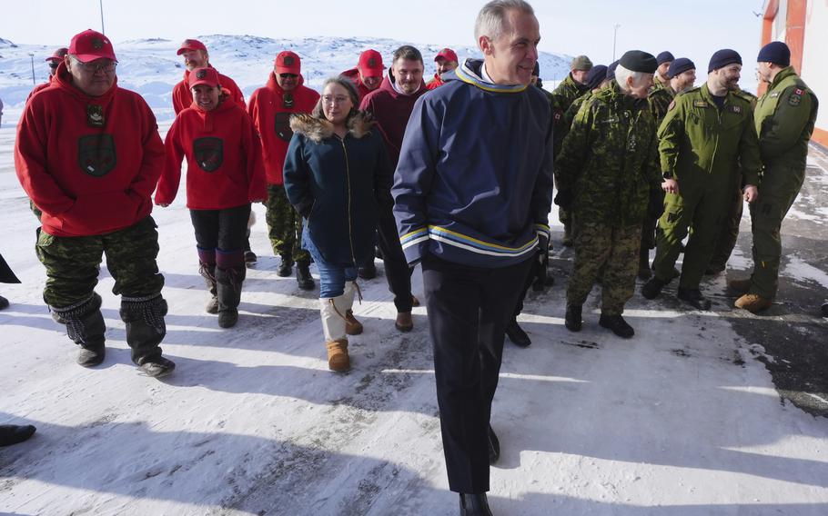 A man walks with a group of people at a military area in Canada.