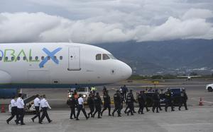 Costa Rican Airport personnel walk towards a plane carrying migrants in the country.