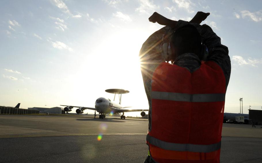 Airman 1st Class Quincy Jackson signals an E-3 Sentry Airborne Warning and Control aircraft to halt Jan. 28, 2014, at Kadena Air Base, Japan.