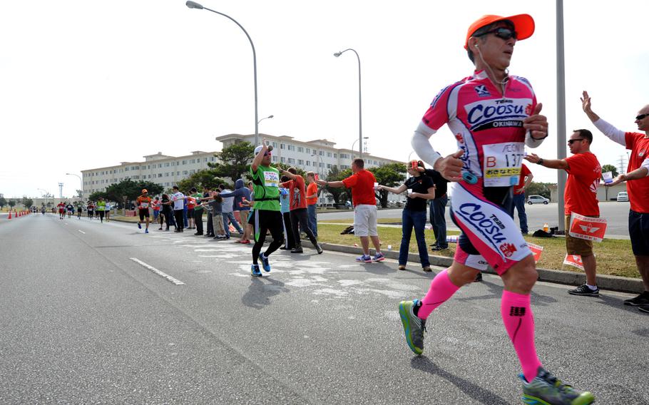 Runners are cheered on by volunteers during the 2015 Okinawa Marathon as they follow the route through Kadena Air Base, on Feb. 15, 2015.