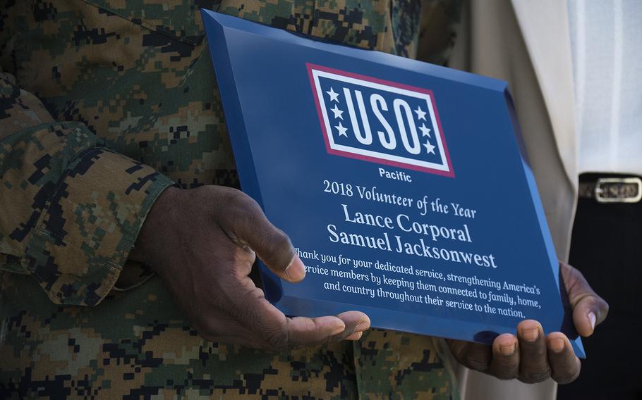 Lance Cpl. Samuel Jacksonwest of Combat Logistics Battalion 4 holds his USO Pacific volunteer of the year award at Camp Foster, Okinawa, Nov. 28, 2018.