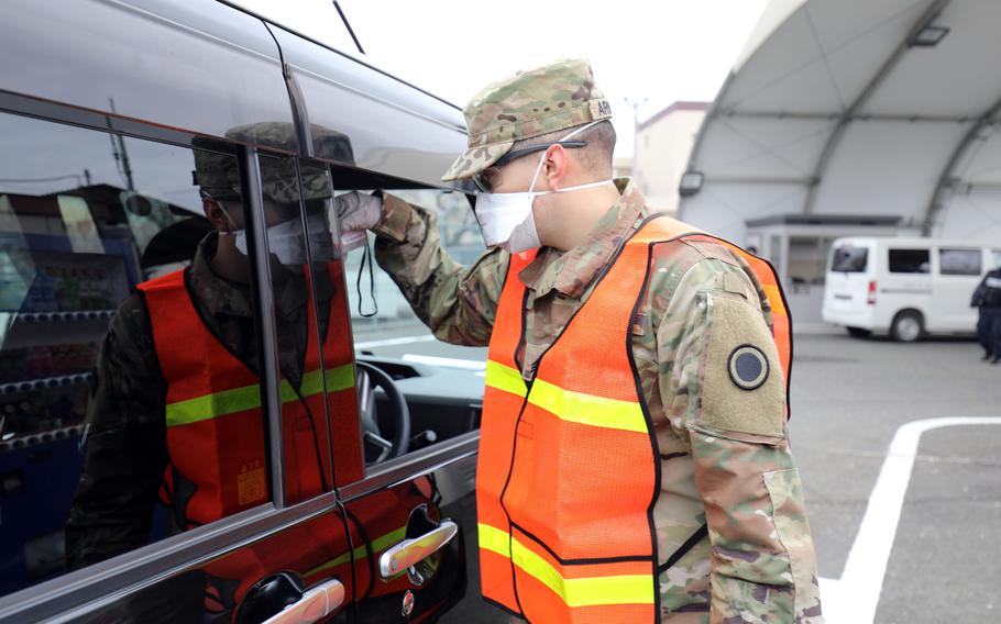 A soldier takes the temperature of a driver at Camp Zama, Japan, March 31, 2020 to screen for coronavirus.